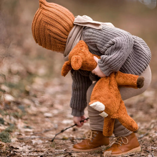 Child in warm winter clothing hugging a Cuddly Toy Deer Small