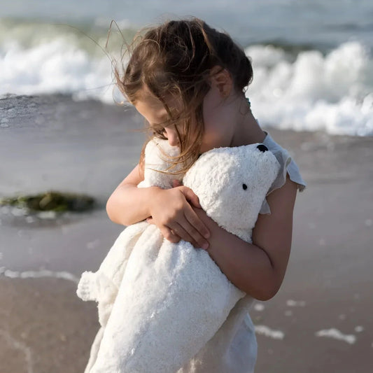 Child lovingly hugging the white Senger Naturwelt Plush Toy Seal Large