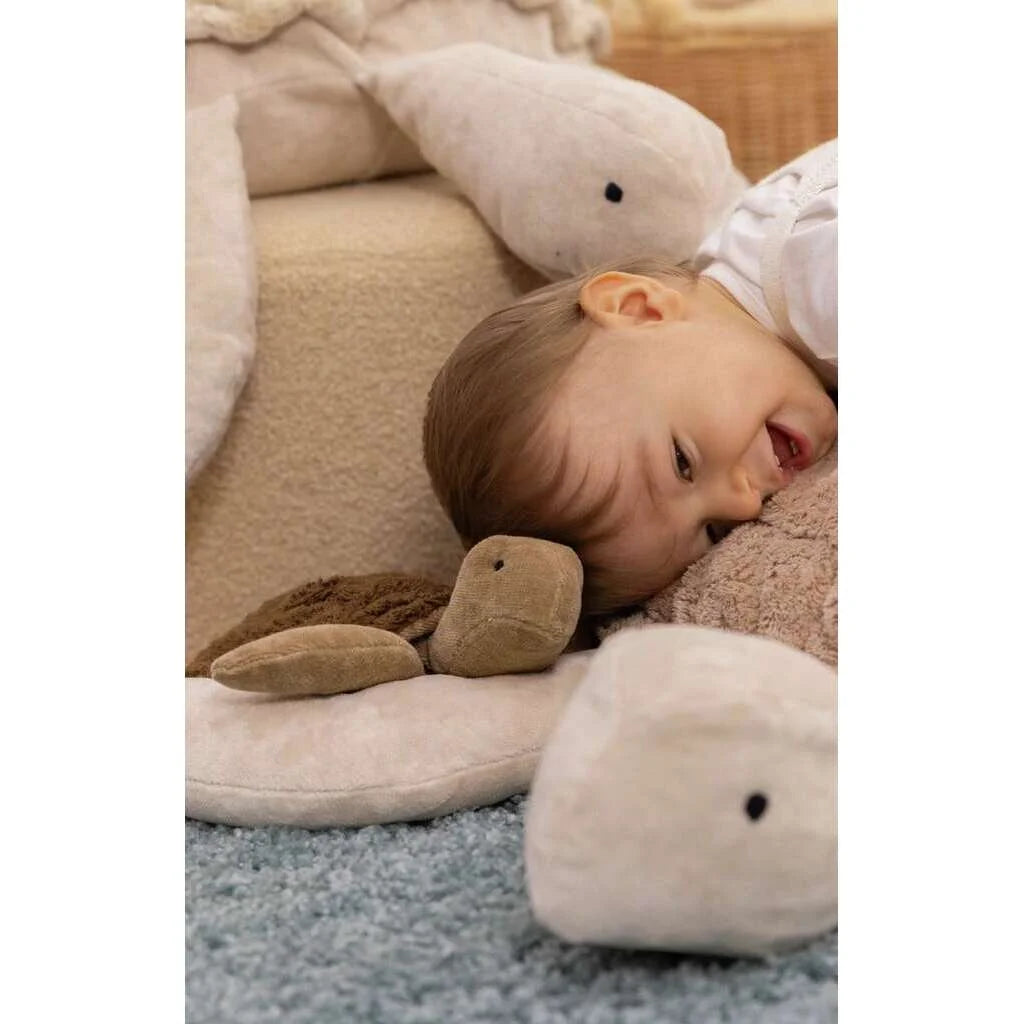 Ein Baby liegt entspannt zwischen weißen Wal-Plüschspielzeugen