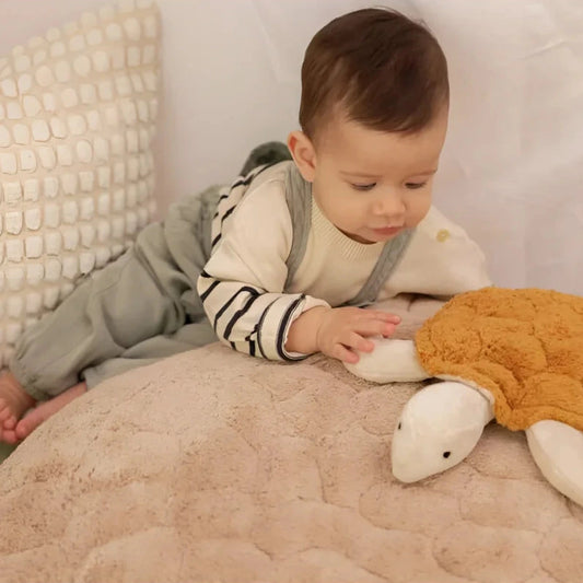Baby with the small turtle cuddly toy in brass