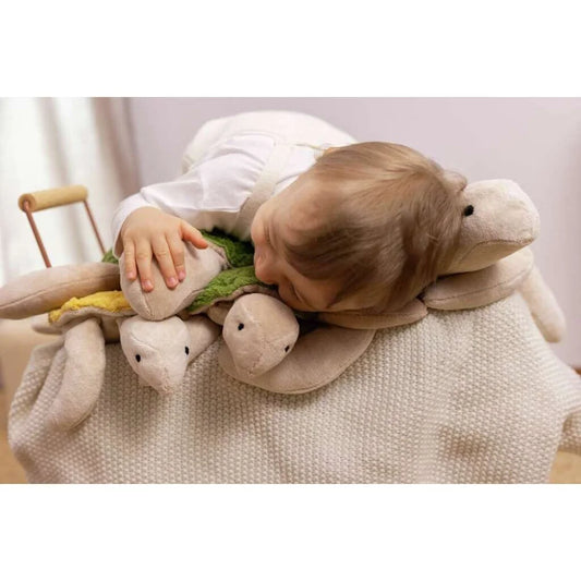 Kind ruht auf kuscheligen Schildkröten-Spielzeugen in tannengrün