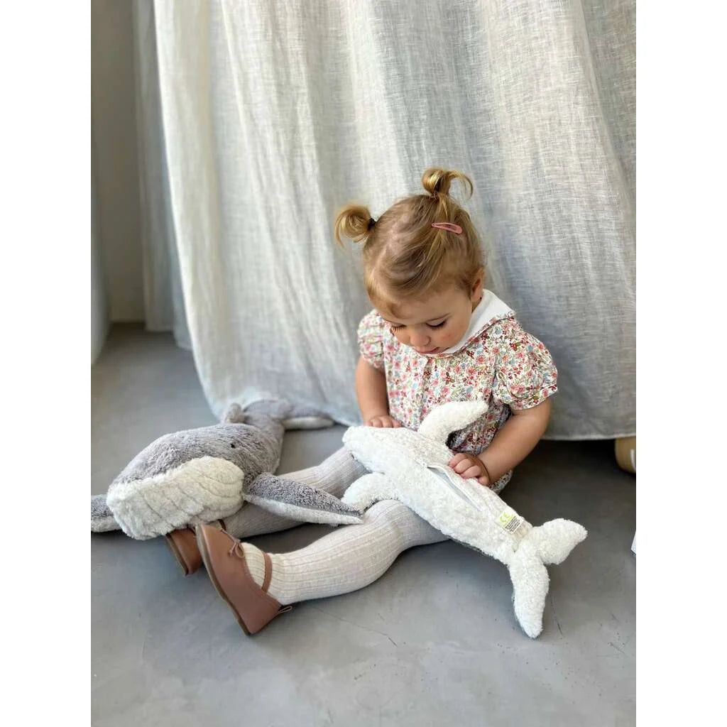 Junge spielt mit einem großen Plüschwal auf dem Boden