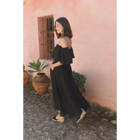 Frau in Off-Shoulder-Schwarzes Leinenrock Alba Noir vor stiligem Hintergrund