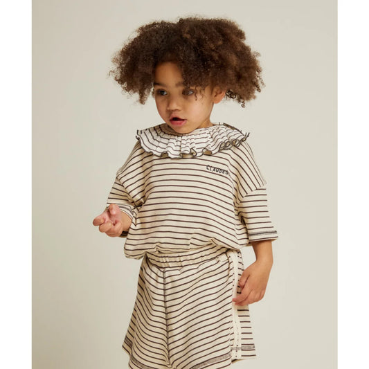 Ein kind trägt ein gestreiftes kurzarmshirt mit gerafftem kragen und passender hose von coudre lenni coco stripe tee