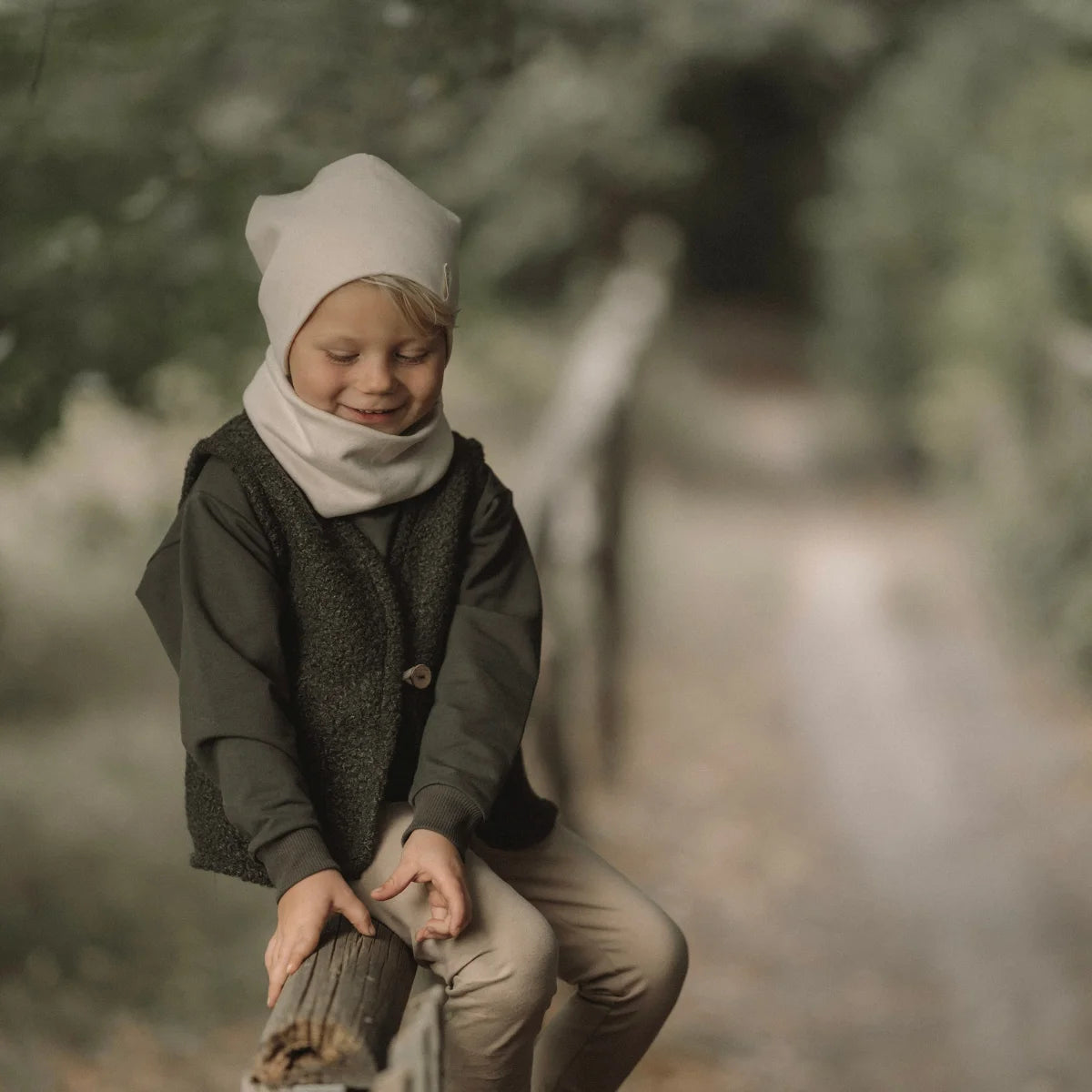 Kinder-Winteroutfit Loop Ecru mit dunkelgrüner Hemd, grauem Weste, beigen Hosen und Mütze