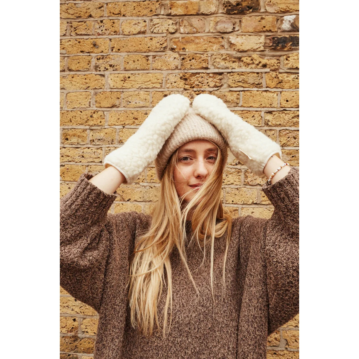 Frau mit Strickmütze und Pullover hebt die Hände am Kopf, Mama Handschuhe Teddy, Milk