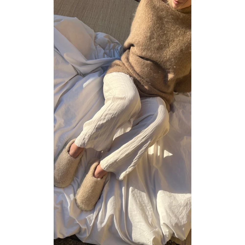 Mutter Schaffell Booties und gemütlicher Pullover auf weißem Bett, Mama Schaffell