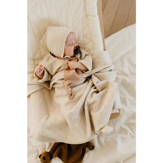 Schlafendes Baby in cremefarbener Decke mit Strickmütze, Merino Strickdecke Bibi