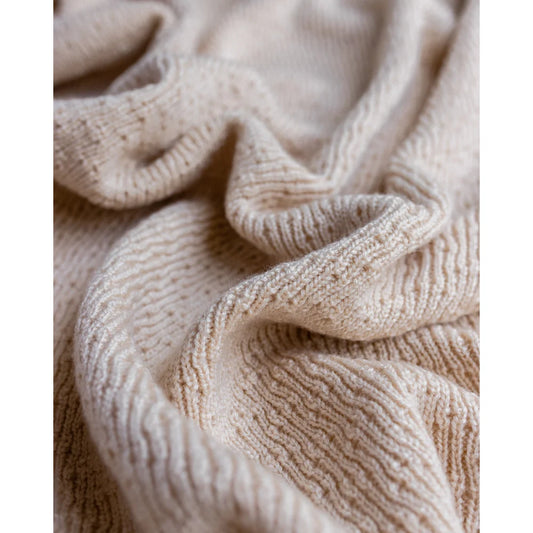 Cremefarbener Strickstoff mit strukturiertem Rippenmuster und Falten von Merino Strickdecke Dora