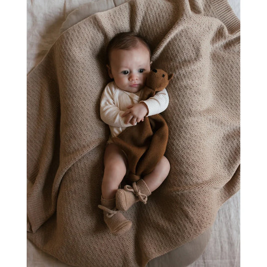 Baby auf beiger Merino Strickdecke Dora hält einen Teddybären