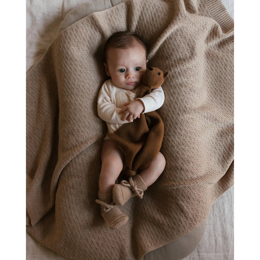 Baby auf beiger Merino Strickdecke Dora hält einen Teddybären