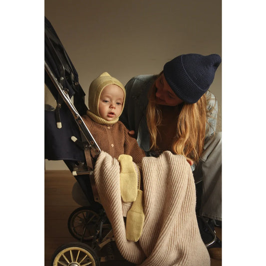 Vintage Baby Stroller with Black Frame and Wheels next to Merino Strickdecke Gaston Soft Beige