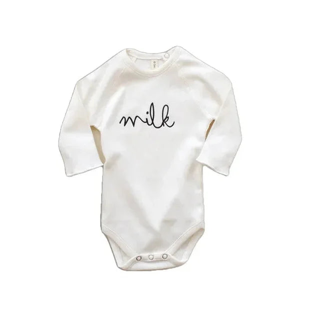 Weiße Baby-Bodys mit Milch in geschwungener Schrift auf der Vorderseite