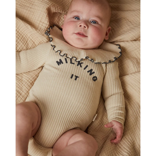 Beige geripptes babybodysuit mit rüschensaum und milking it schwarz bedruckt aus weichem material