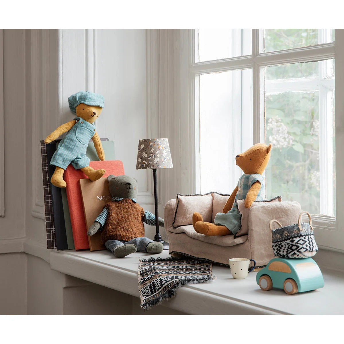 Sammlung von Plüschspielzeugen auf dem Fensterbrett neben der Miniatur-Couch