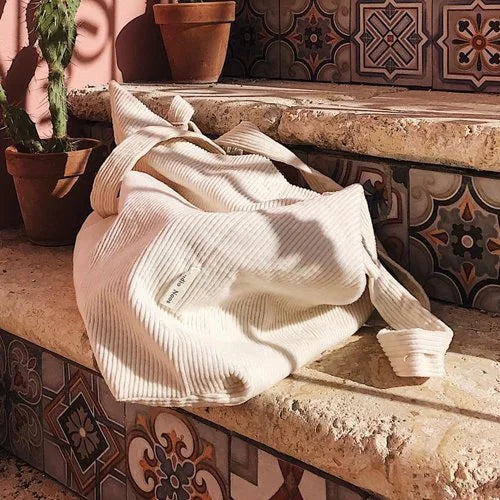 Cremefarbener strukturierter Wurf auf Steinstufen neben Mom Bag Rib in Altweiß