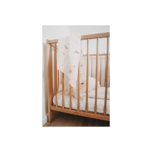 Holz-Kinderbett mit vertikalen Latten und weißem, gemustertem Laken von Mulltuch