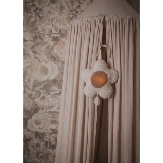 Weißer lampenförmiger Leuchter mit orangefarbenem Zentrum auf Stoffhintergrund