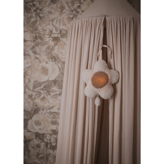 Weißer lampenförmiger Leuchter mit orangefarbenem Zentrum auf Stoffhintergrund