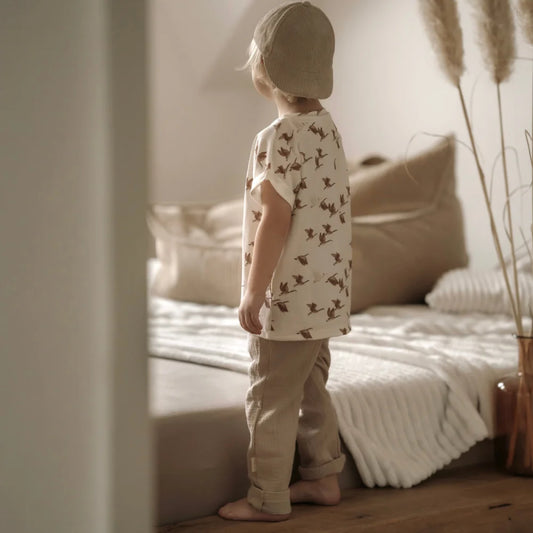 Kind in passendem beigen Outfit mit Musselinhose lang in beige