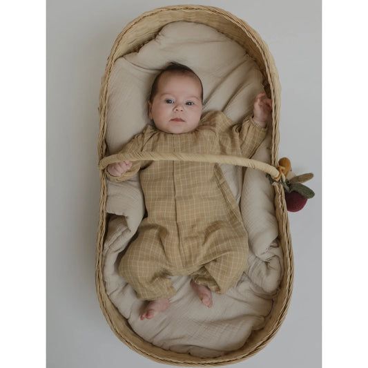 Baby in a gewebtem Kinderbett mit einem Onesie in Weizengelb und Karomuster