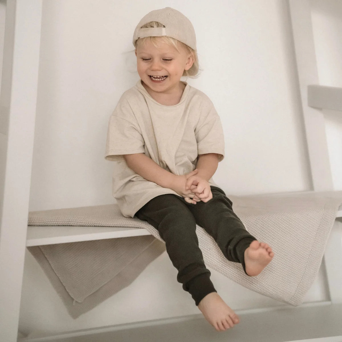 Lächelndes Kind in lässiger Kleidung trägt das beiges Oversized Shirt mit Sprenkelmuster