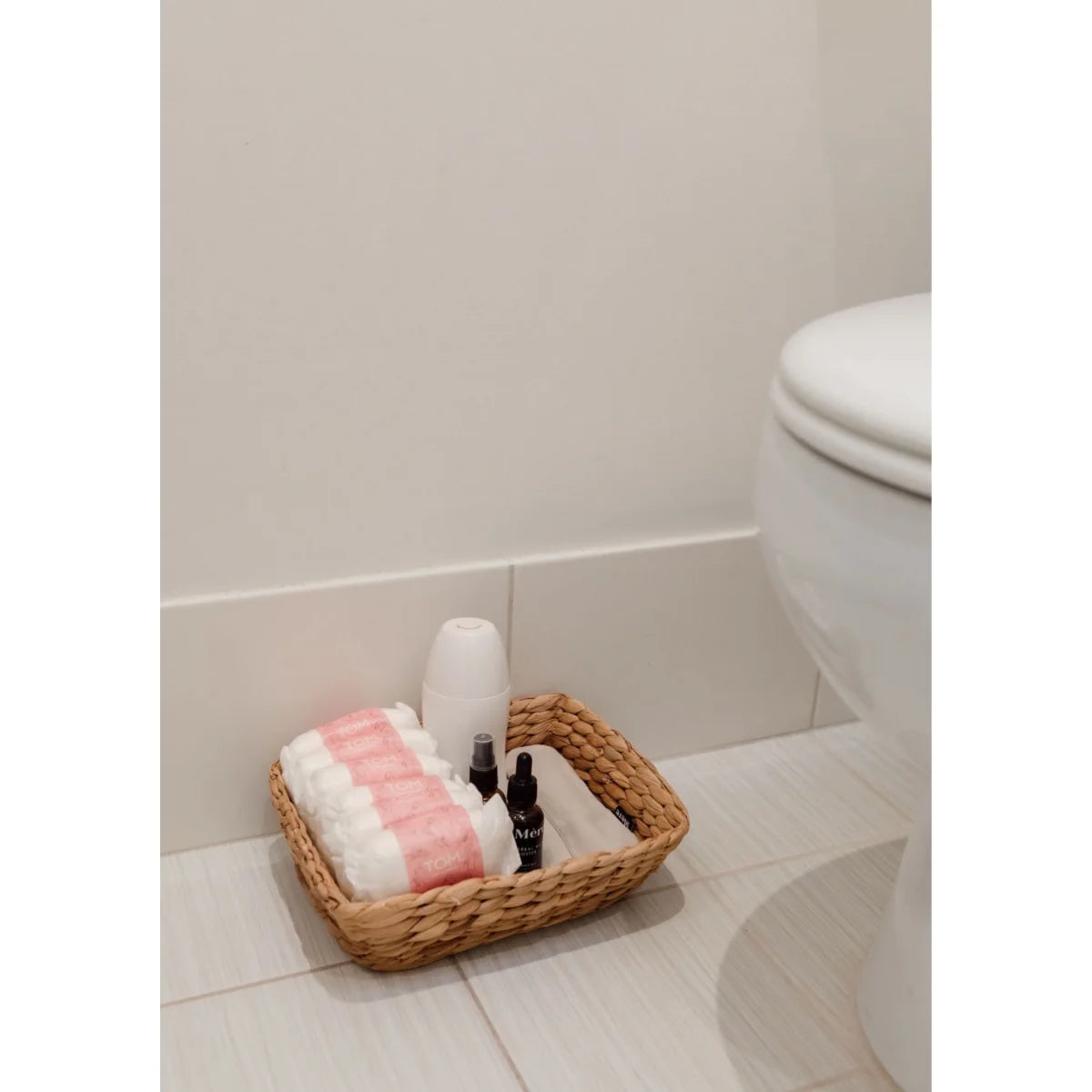 Wäschekorb mit Toilettenartikeln und gerollten Handtüchern für Perinealwaschflasche