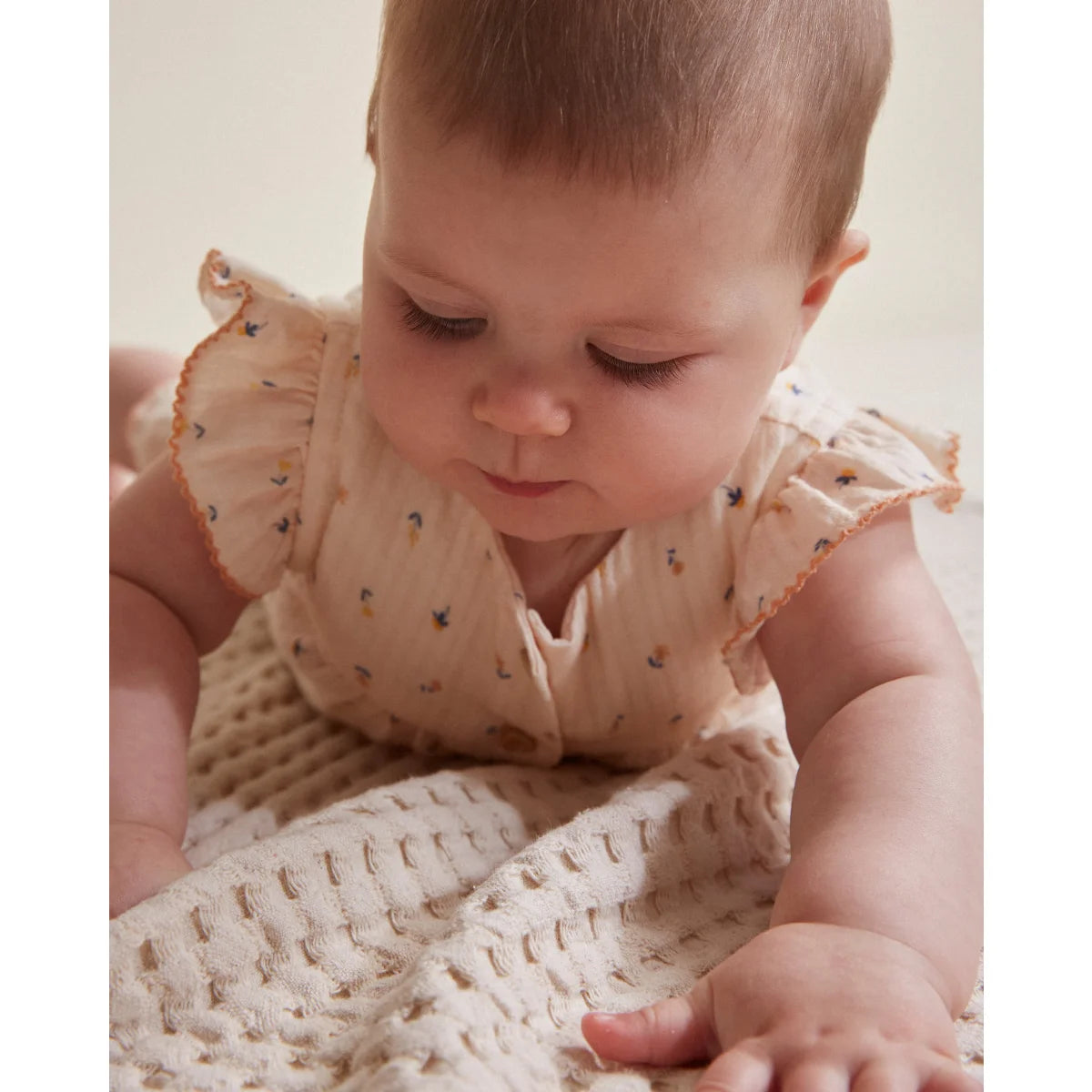 Baby in floral flutter-sleeve dress with knit blanket from Petite Fleur Jumpsuit Unico