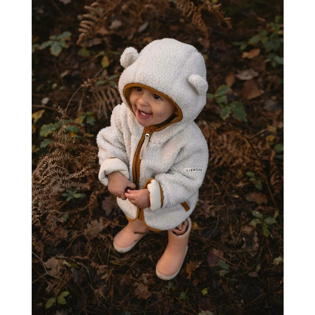 Gemütlicher weißer Teddy-Pullover mit passender Mütze und Stiefeln in Sandkaramell