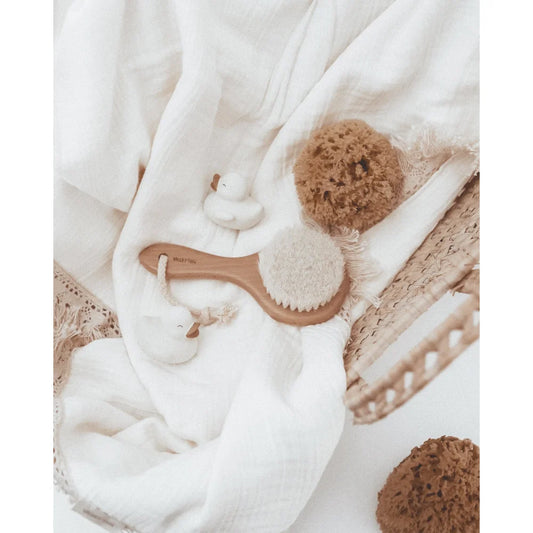 Holzgriff-Bürste mit weichen Borsten auf weißem Stoff im Badeset von Polly & Olly