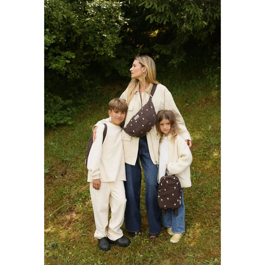 Mutter und zwei Kinder in stilvollen, abgestimmten Outfits mit braunen Herztaschen