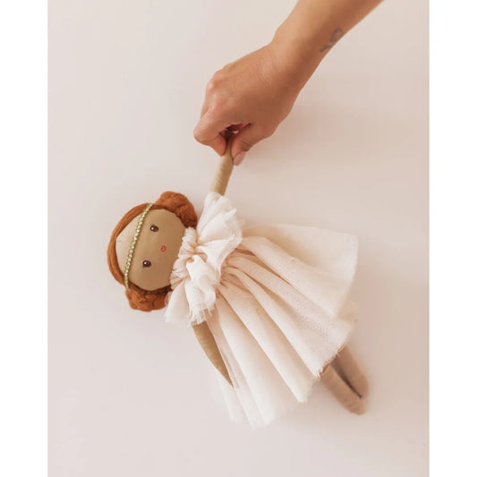 Weiche Plüschpuppe mit braunen Haaren im weißen Kleid, von einer Hand gehalten