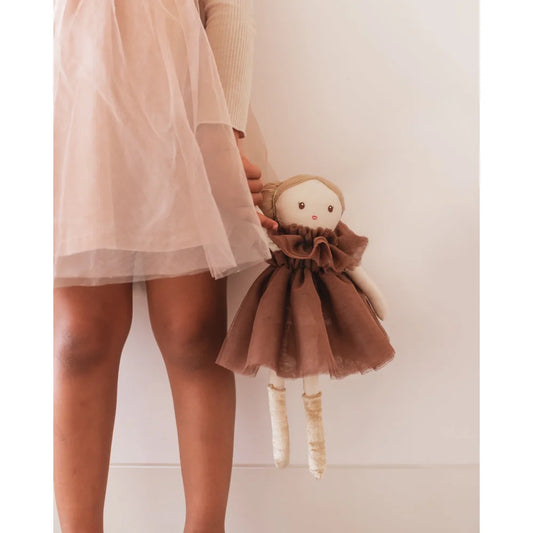 Handgemachte Stoffpuppe mit brauem Kleid, gehalten von Person in hellpinkem Kleid