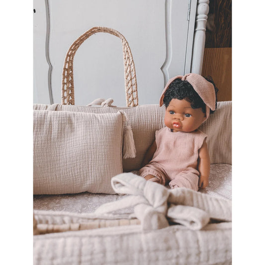 Baby-Puppe Loreta in pink Kleidung und Haarband neben einem geflochtenen Korb