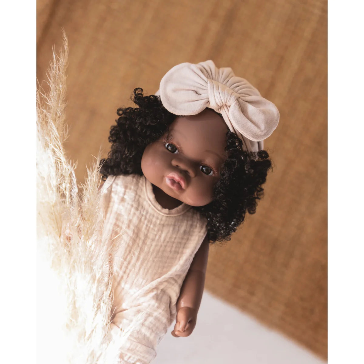 Dunkelhäutige Baby-Puppe Loreta mit lockigem schwarzem Haar und weißem Kleid