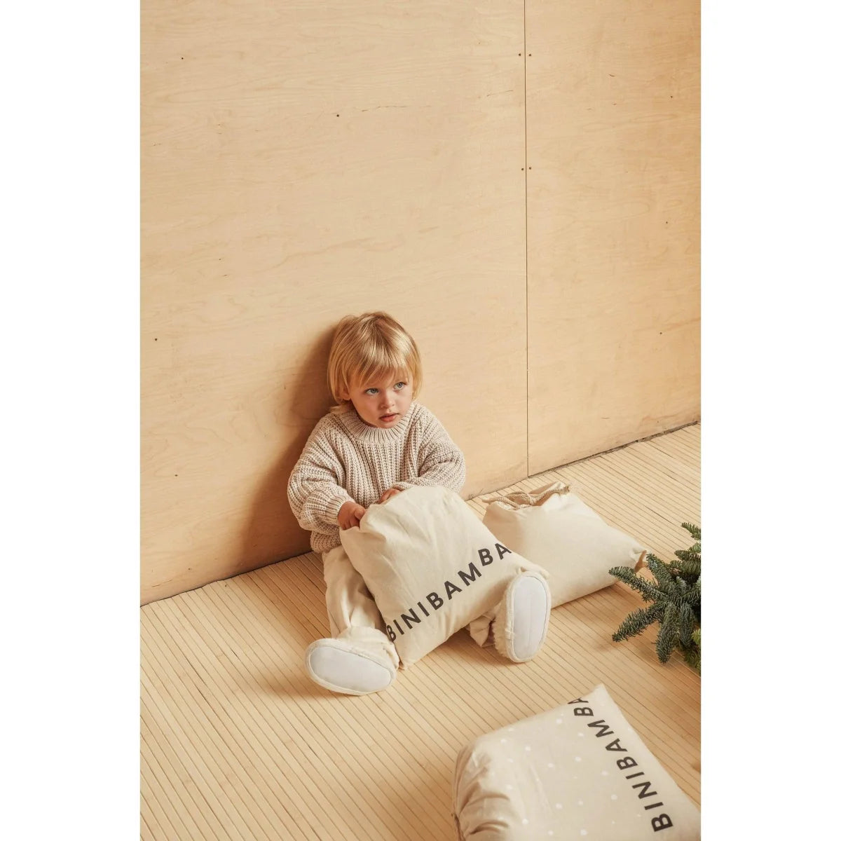 Junger Junge sitzt auf dem Boden mit Kissen, die Binibamba beschriftet sind