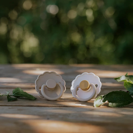 Zwei silikon schnuller daisy in kamille und croissant mit gewelltem rand und goldfarbiger latex nippel für babys 6 bis 18 monate ökologisch und nachhaltig