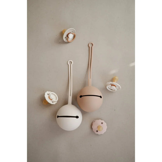 Zwei runde, beige Objekte mit dünnen Stielen und einfachen Linienmündern im Schnuller Etui