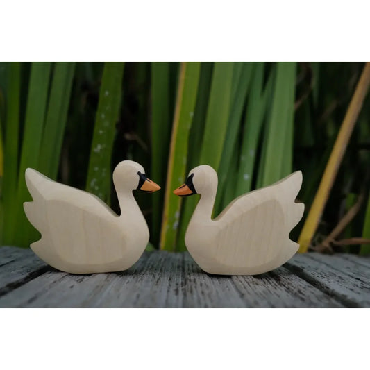 Zwei hölzerne Schwanenfiguren mit schwarzen und orangefarbenen Schnäbeln