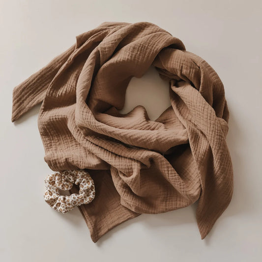 Helle, beigefarbene Baumwollschal in Kreisform mit floraler Brosche dekoriert