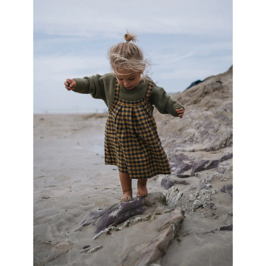 Junge im grünen Pullover und kariertem Pinafore für den Artichoke Wool Jumper