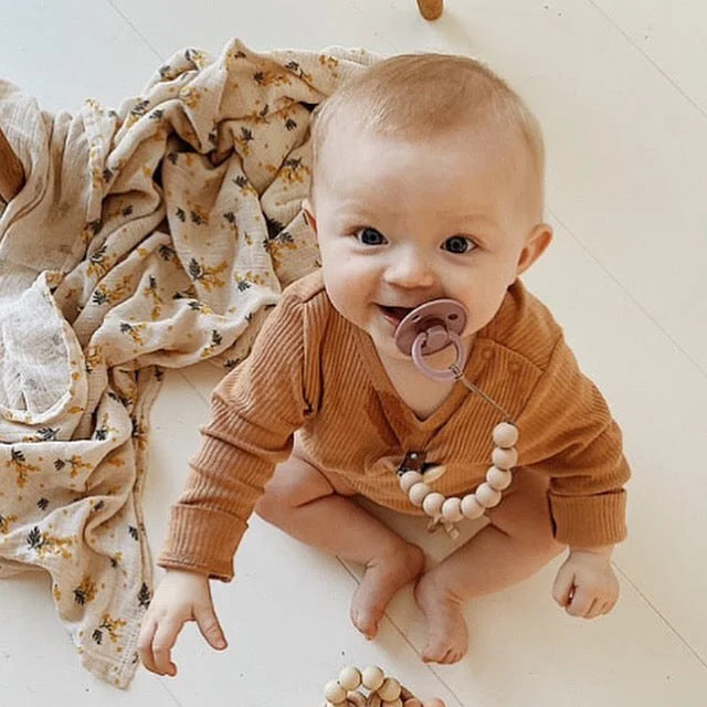 Lächelndes Baby mit Schnuller an Silikon Nuggikette aus Baumwolle