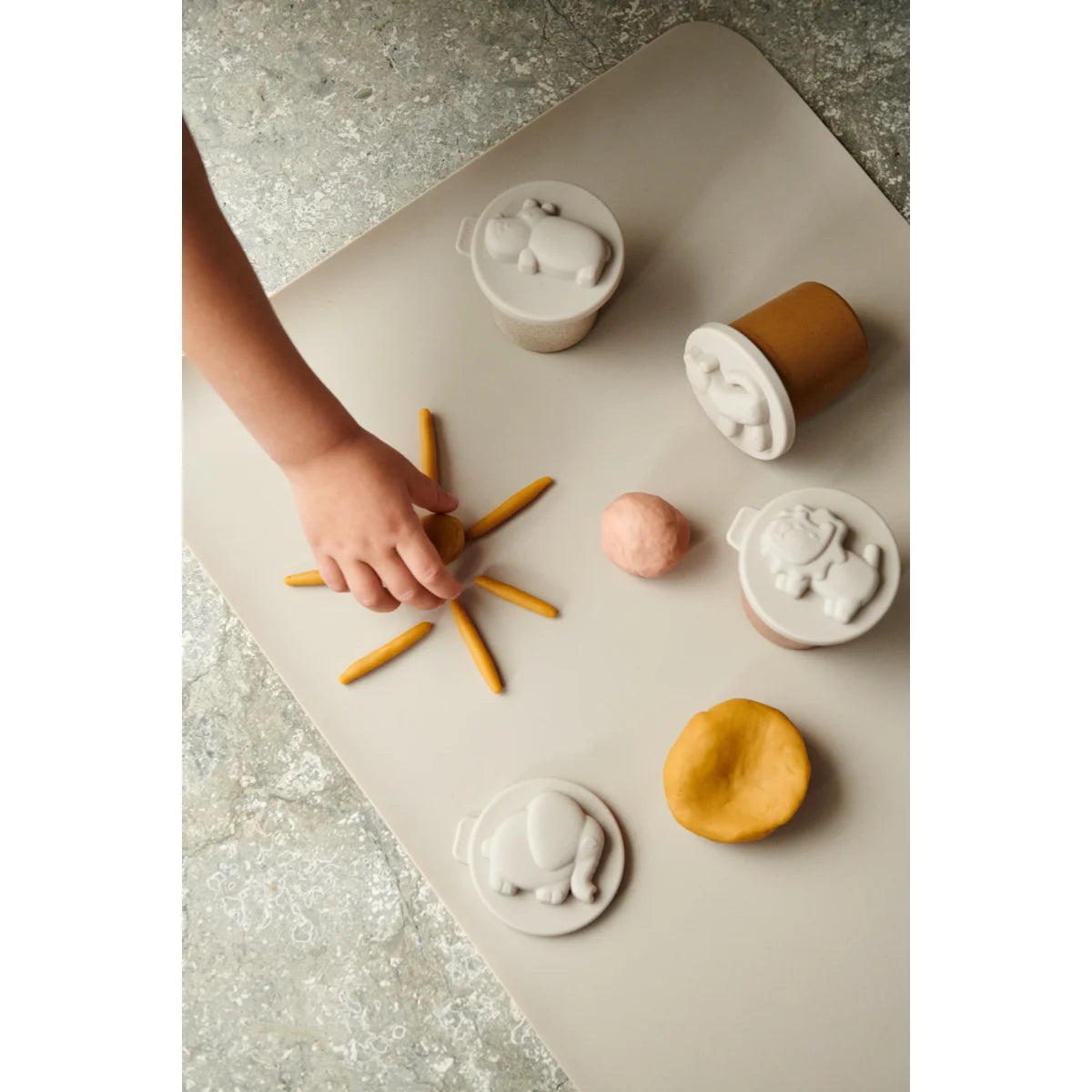 Eine Hand arrangiert Pommes frites in einem Sternmuster im Spielknete Set Rollie