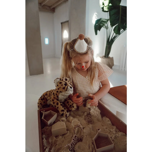 Junge mit Zirkus-Spielset, spielt mit magischem Sand und Cheetah-Plüsch in der Schweiz