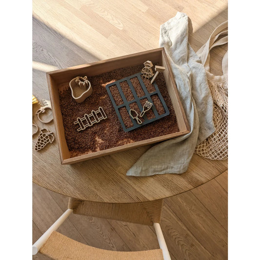 Holz-Sinneswanne mit braunen Samen und Gartenwerkzeugen für kindliches Spielen