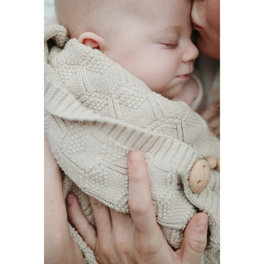 Schlafendes Kleinkind in einer cremefarbenen Strickdecke Honeycomb Beige
