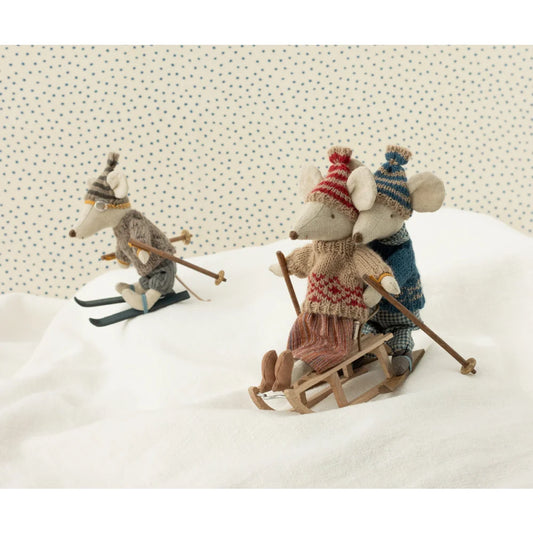 Drei Spielzeugmäuse beim Skifahren auf dem Strickpullover und Mütze von Mama Maus