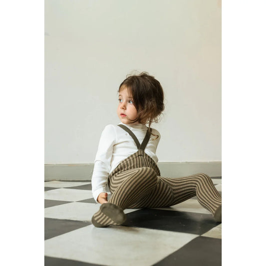 Kleiner Junge in gestreiften Trägerstrumpfhosen und weißem Langarmshirt