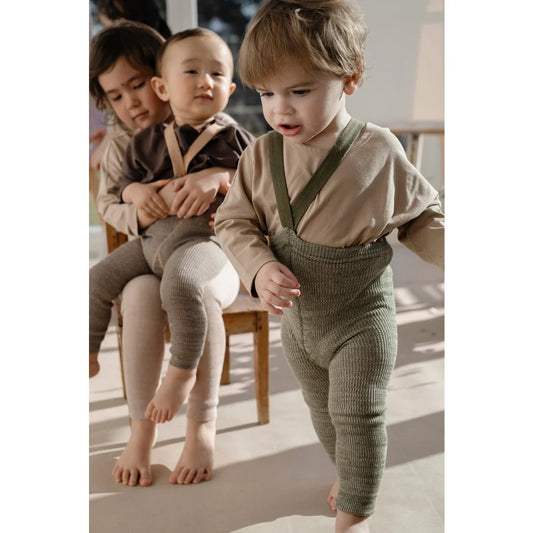 Drei Kinder in Strumpfhosen mit Trägern aus cremegrünem Material