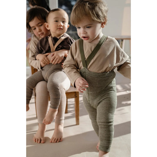 Drei Kinder in Strumpfhosen mit Trägern aus cremegrünem Material